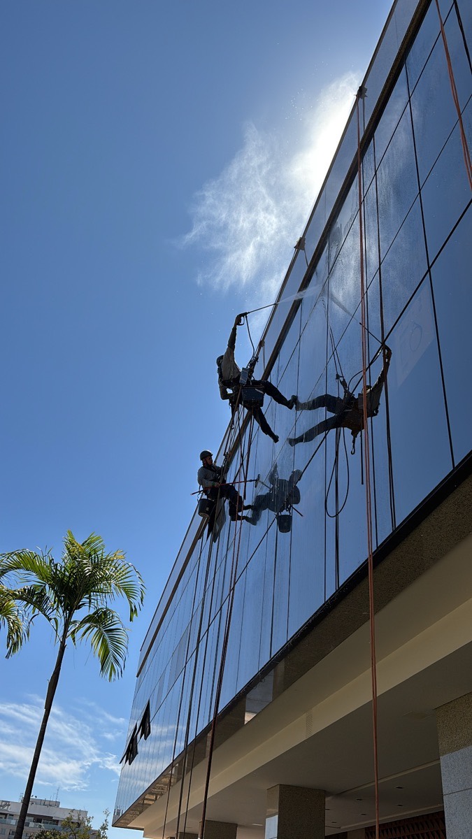 Alpinistas industriais em rapel limpando fachada envidraçada de edifício
