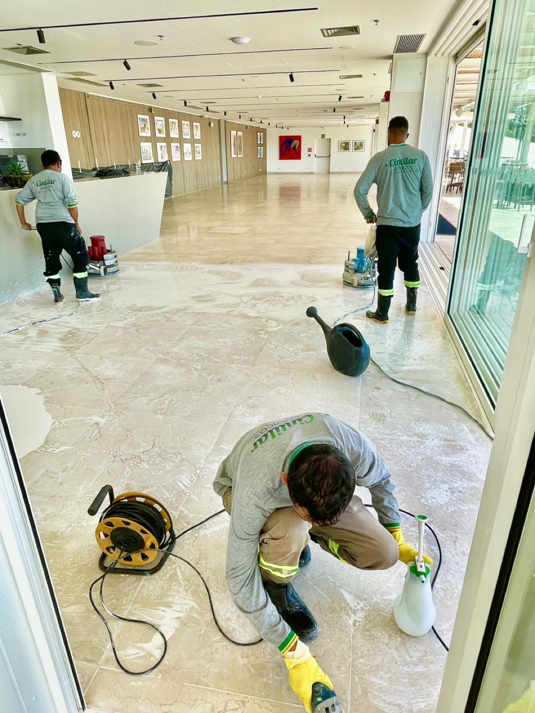 Equipe Cintilar uniformizada revitalizando piso de travertino em galeria corporativa