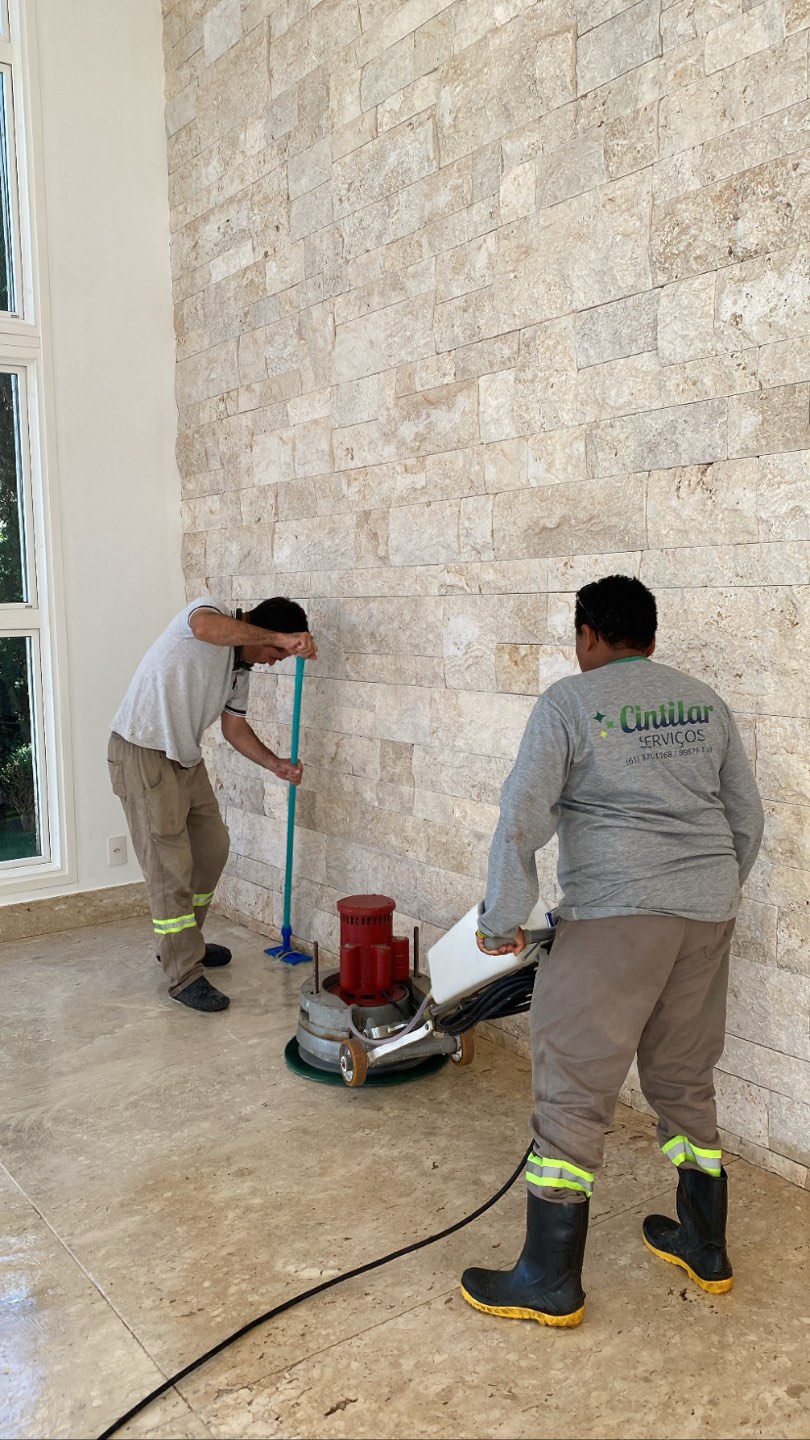 Equipe Cintilar uniformizada revitalizando piso de pedra ao lado de parede de mármore travertino